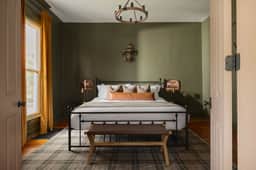 Cozy, stylish bedroom with king bed, rustic chandelier & sunlit window